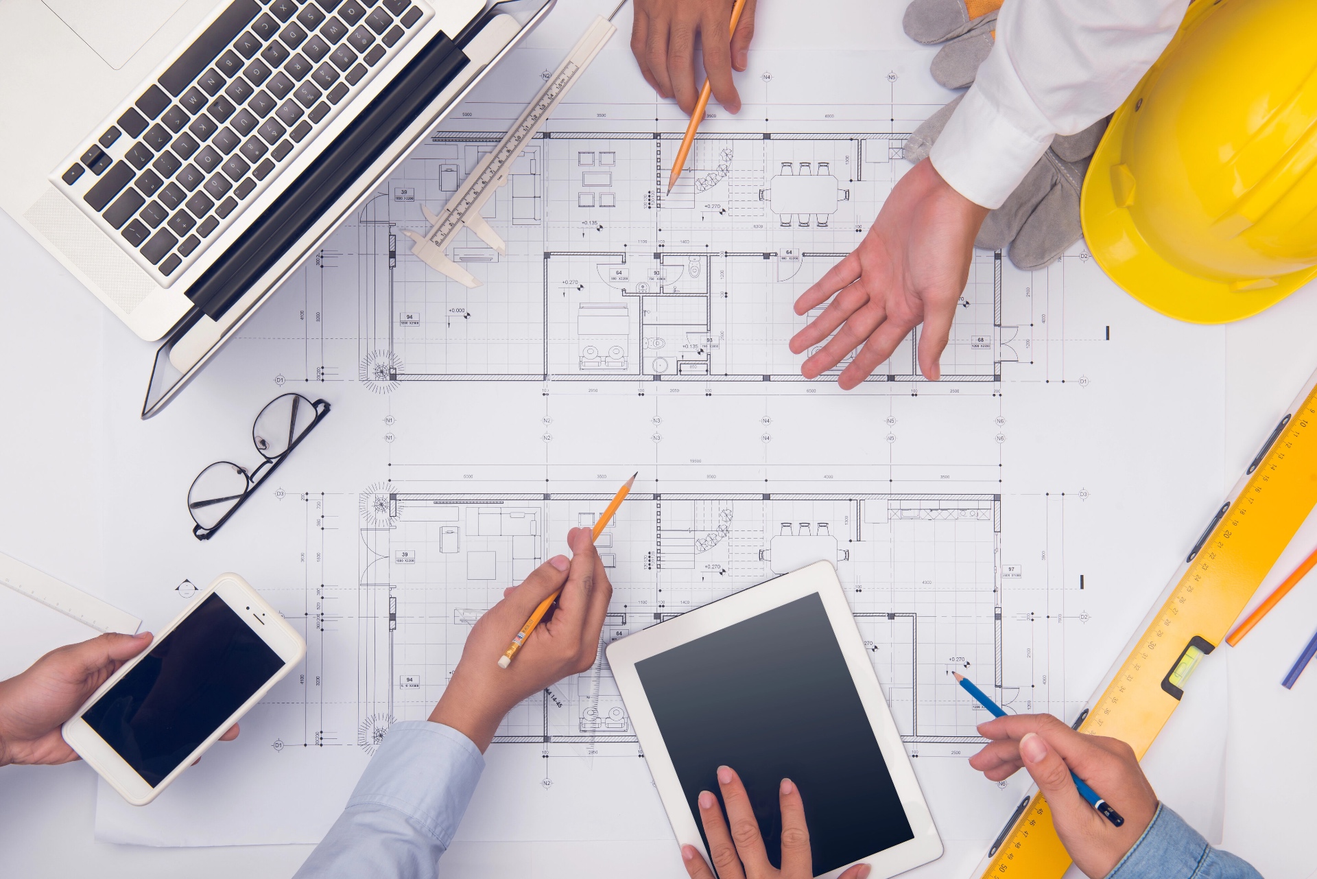 YourKeys team reviewing architectural blueprints around a worktable