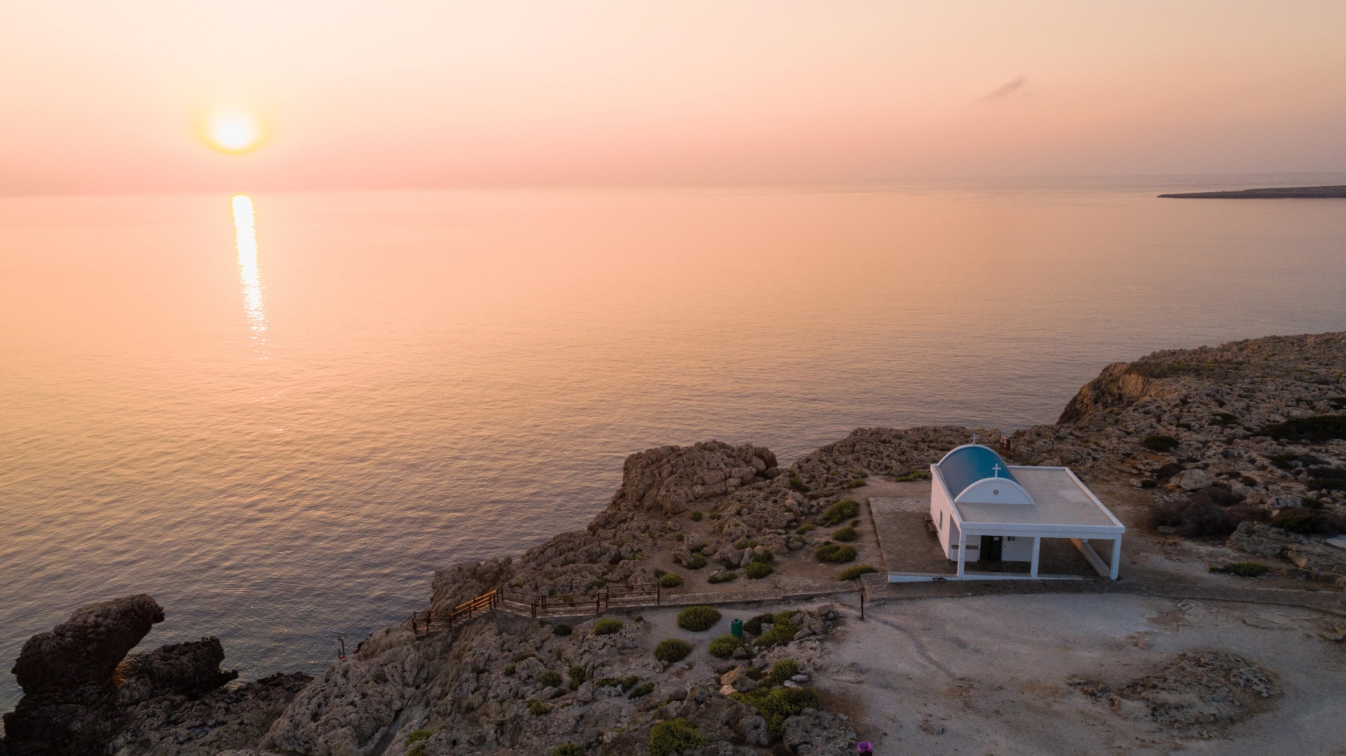 Whitewashed stone chapel above the Mediterranean sea at golden hour